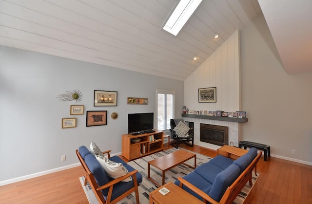 living room with vaulted ceiling with skylight, light hardwood / wood-style floors, and a fireplace