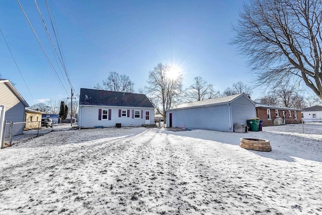 snow covered back of property featuring an outdoor fire pit