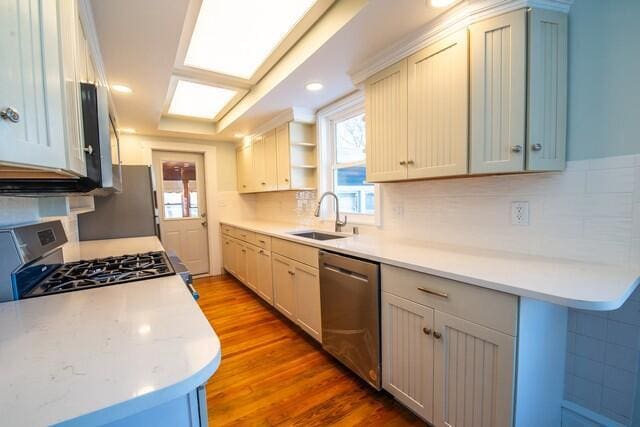 kitchen featuring backsplash, hardwood / wood-style floors, sink, white cabinetry, and stainless steel appliances