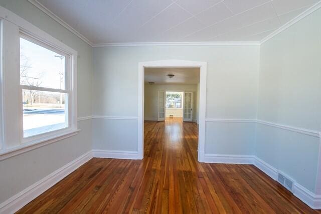 empty room featuring dark wood-type flooring and ornamental molding