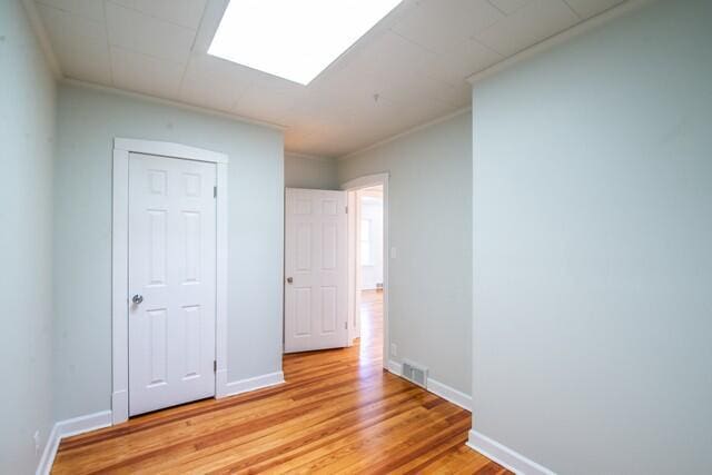 spare room with ornamental molding and light hardwood / wood-style flooring