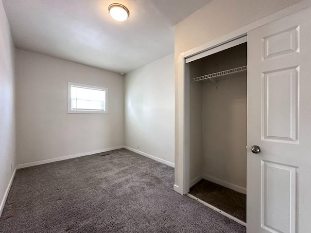 unfurnished bedroom featuring a closet and dark carpet