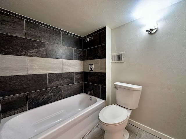 bathroom with tiled shower / bath combo, toilet, and tile patterned flooring