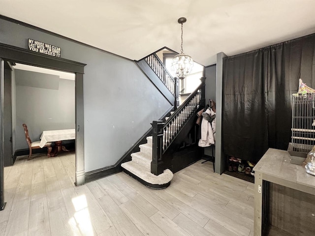 foyer entrance with light wood-type flooring, a notable chandelier, and crown molding