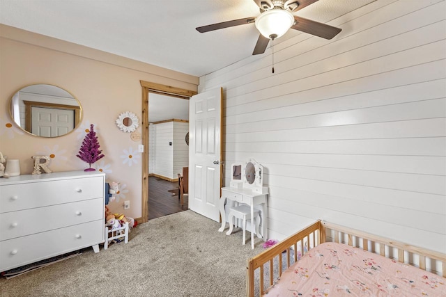 unfurnished bedroom featuring ceiling fan, wood walls, and carpet floors