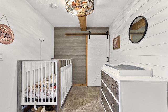 bedroom with a barn door, a nursery area, beamed ceiling, and wooden walls