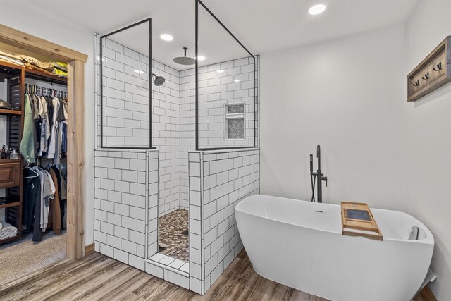 bathroom featuring wood-type flooring and shower with separate bathtub