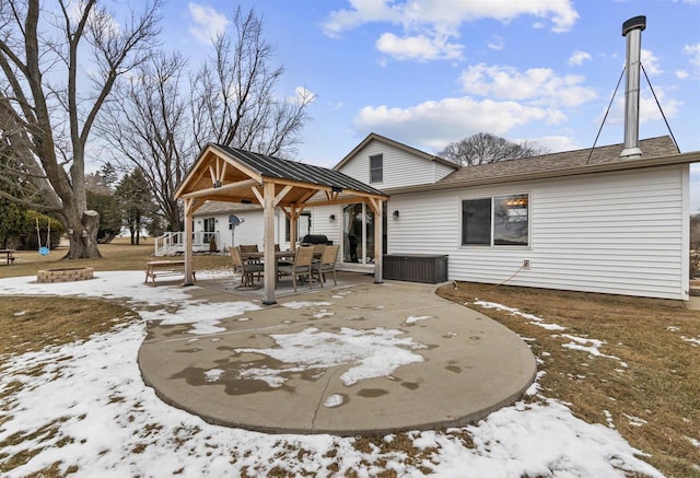 snow covered back of property with a patio and a fire pit