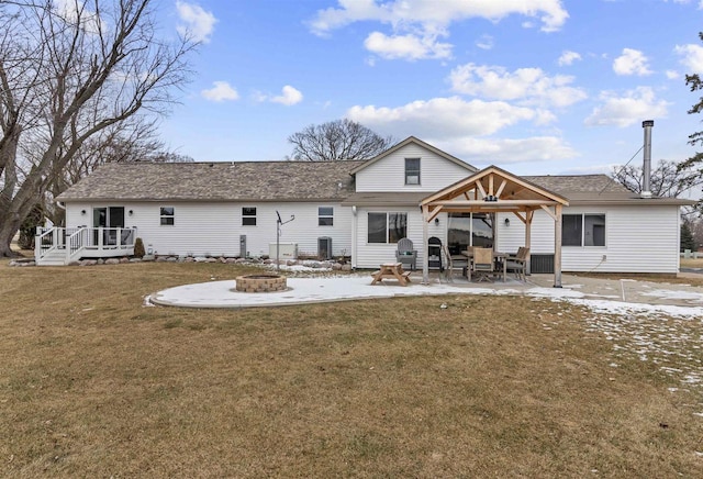 back of house featuring a yard, a deck, a patio, and a fire pit