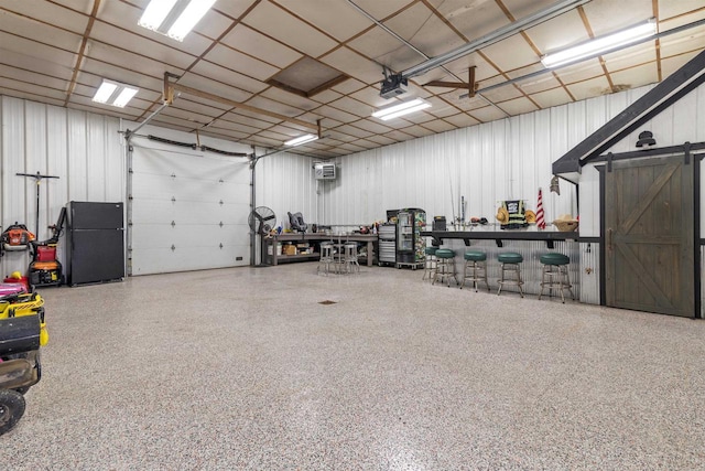 garage featuring black fridge, a garage door opener, and a wall mounted air conditioner