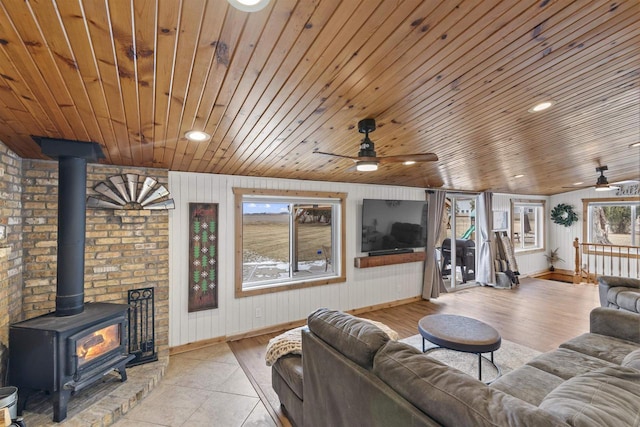 living room with plenty of natural light, a wood stove, and wooden ceiling