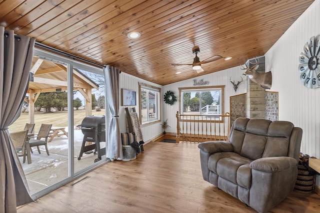 living area with ceiling fan, lofted ceiling, wood walls, light hardwood / wood-style flooring, and wood ceiling