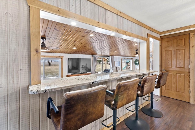 kitchen featuring dark wood-type flooring, ceiling fan, and wood walls