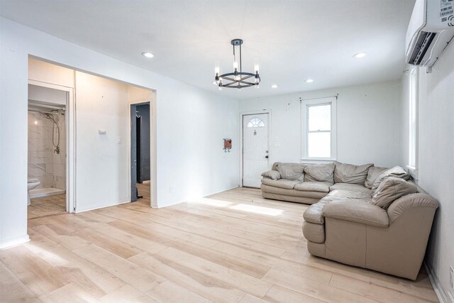 living room with a wall mounted air conditioner, a notable chandelier, and light hardwood / wood-style floors