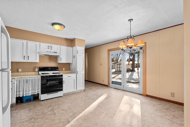 kitchen with white cabinets, decorative light fixtures, wooden walls, a chandelier, and gas range oven