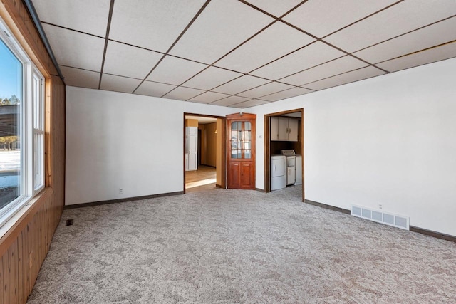 unfurnished room featuring light carpet, washer and clothes dryer, and a drop ceiling