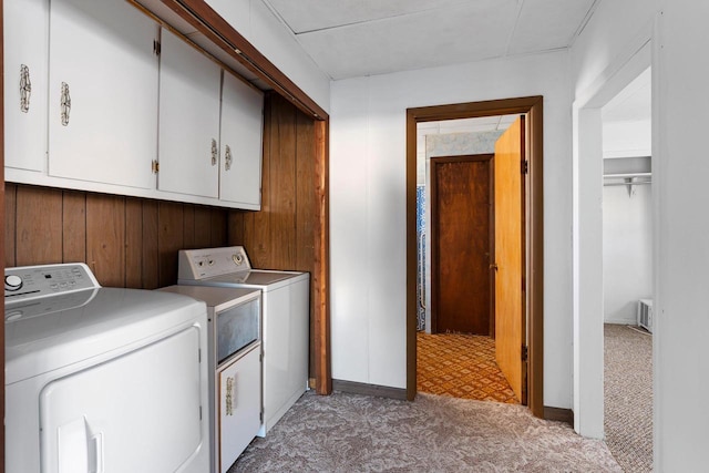 clothes washing area featuring cabinets, light carpet, independent washer and dryer, and wooden walls