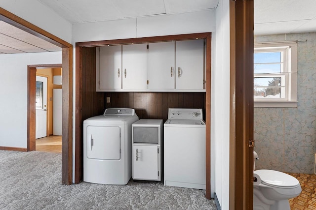 laundry area featuring cabinets, separate washer and dryer, and light colored carpet