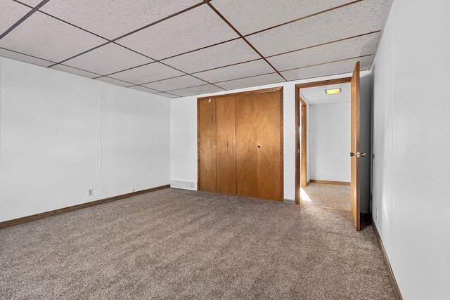 unfurnished bedroom featuring carpet floors, a closet, and a drop ceiling