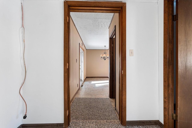 hallway featuring a textured ceiling and a notable chandelier