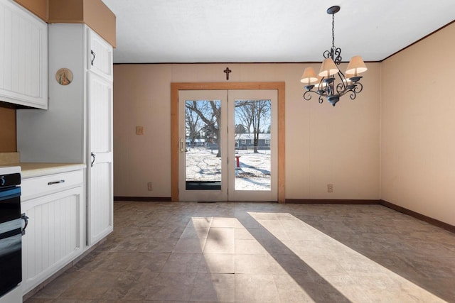 unfurnished dining area featuring a chandelier and french doors