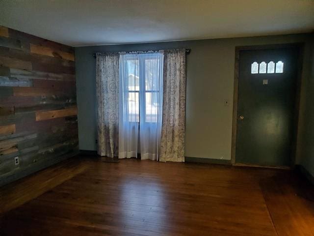 interior space with dark hardwood / wood-style floors and wood walls