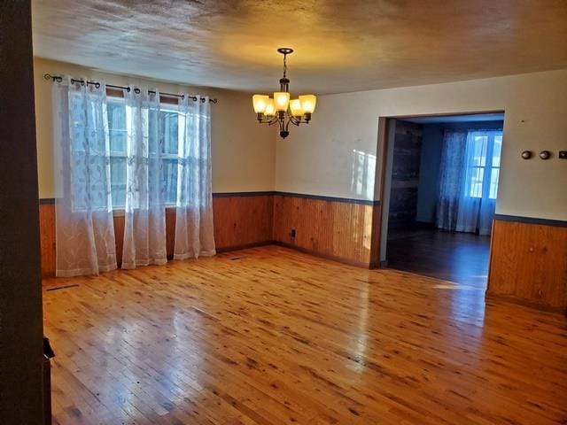 unfurnished room with a chandelier and wood-type flooring