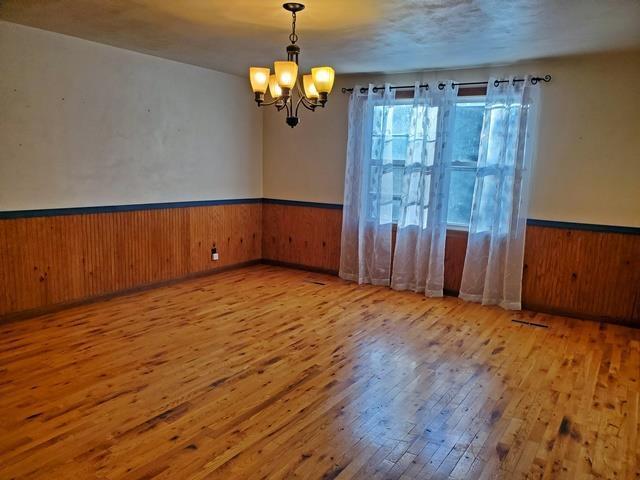 spare room with an inviting chandelier and light wood-type flooring