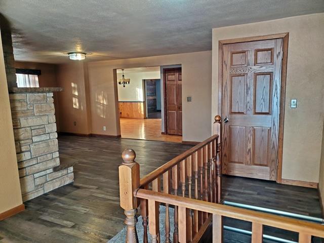 entryway featuring dark hardwood / wood-style flooring, an inviting chandelier, and a stone fireplace