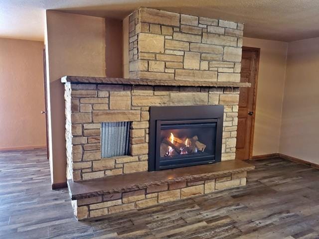 interior details with hardwood / wood-style floors, a textured ceiling, and a stone fireplace