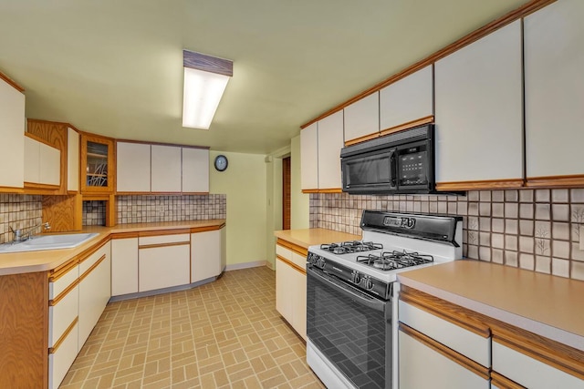 kitchen featuring sink, white cabinetry, backsplash, and gas range gas stove