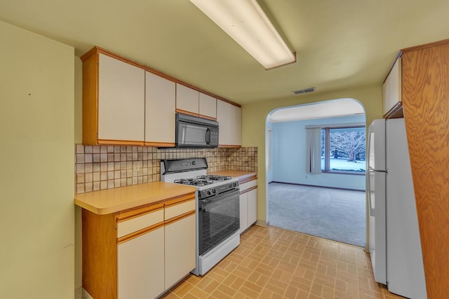 kitchen featuring decorative backsplash, white cabinets, and white appliances