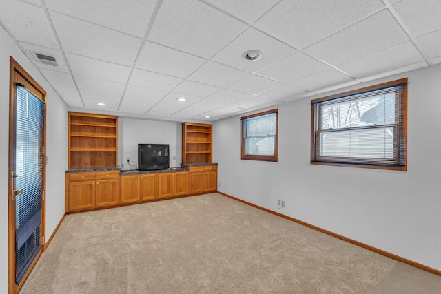 unfurnished living room with a paneled ceiling and light carpet