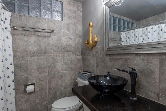 bathroom featuring toilet, tile walls, a shower with curtain, and sink