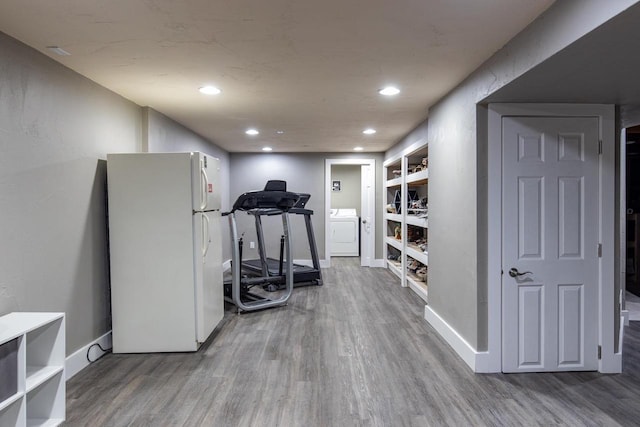 exercise room featuring wood-type flooring and washer / dryer