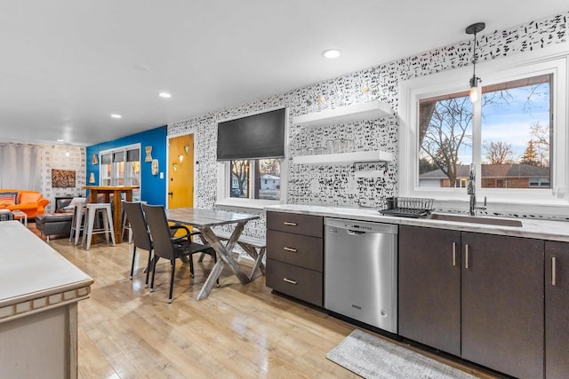 kitchen featuring light hardwood / wood-style floors, dark brown cabinets, dishwasher, hanging light fixtures, and sink