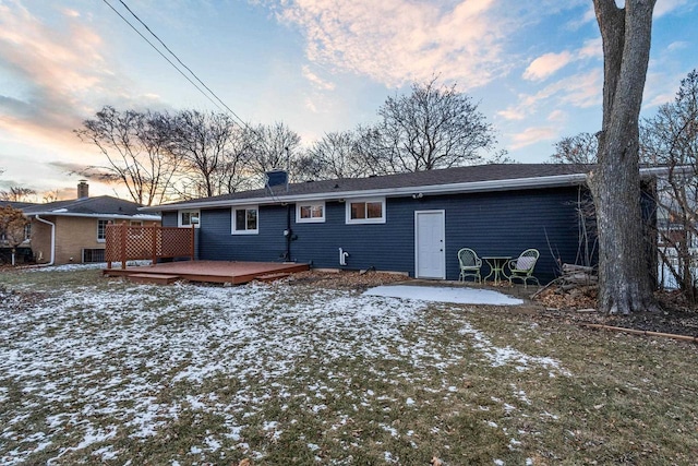 snow covered back of property featuring a deck and a patio