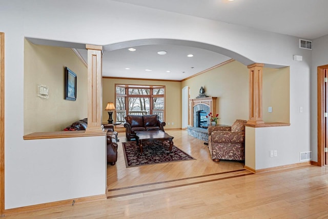 living room featuring decorative columns, light hardwood / wood-style flooring, and crown molding