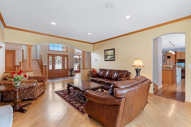 living room with decorative columns, ornamental molding, and light hardwood / wood-style floors