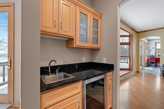 kitchen with light wood-type flooring, wine cooler, dark stone counters, crown molding, and sink