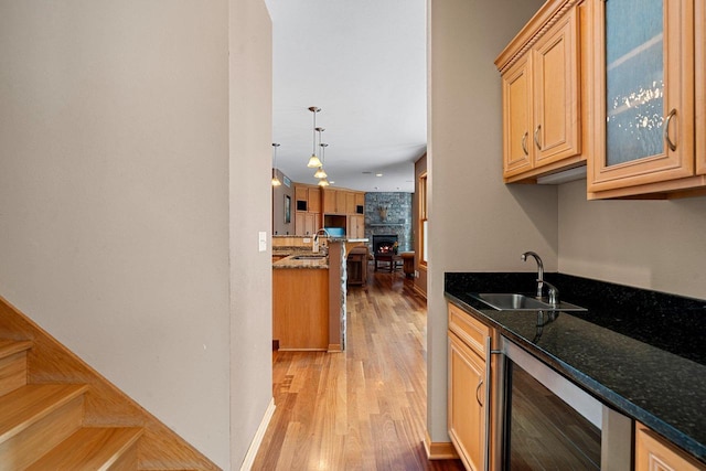 kitchen featuring decorative light fixtures, sink, beverage cooler, and dark stone counters