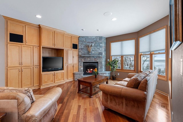 living room with light hardwood / wood-style flooring and a stone fireplace