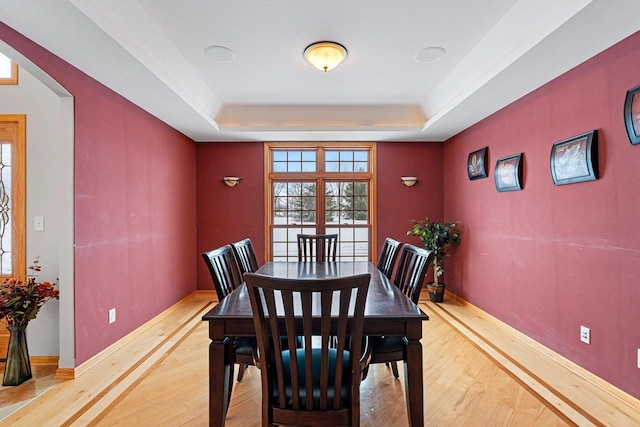 dining room with light hardwood / wood-style floors and a tray ceiling