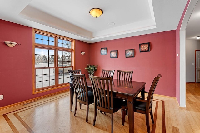 dining area featuring light hardwood / wood-style flooring and a raised ceiling