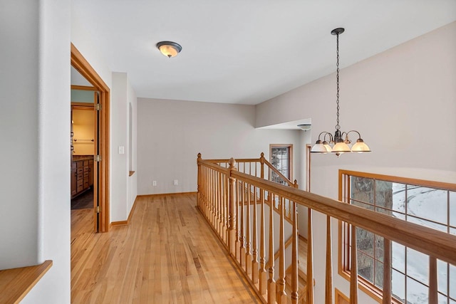 hall featuring light wood-type flooring and an inviting chandelier