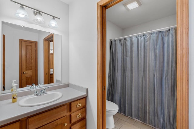 bathroom with toilet, vanity, and tile patterned flooring