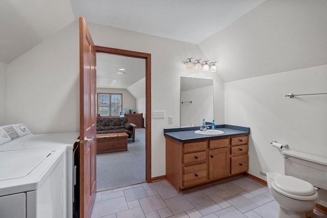 bathroom with toilet, vanity, vaulted ceiling, tile patterned floors, and washer / clothes dryer