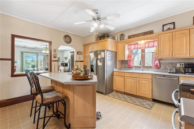 kitchen featuring ceiling fan, stainless steel appliances, sink, baseboard heating, and a center island