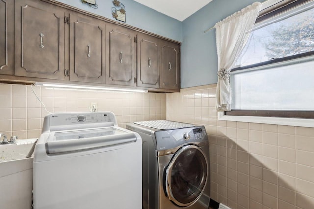 clothes washing area featuring cabinets, sink, and washing machine and clothes dryer