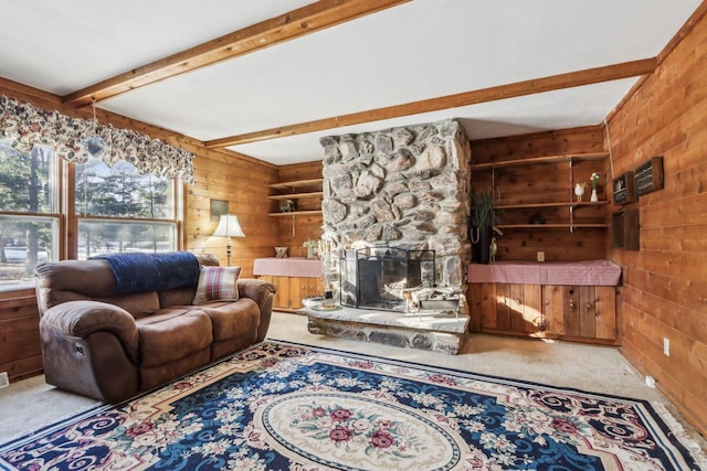 living room with wooden walls, beam ceiling, plenty of natural light, and a stone fireplace